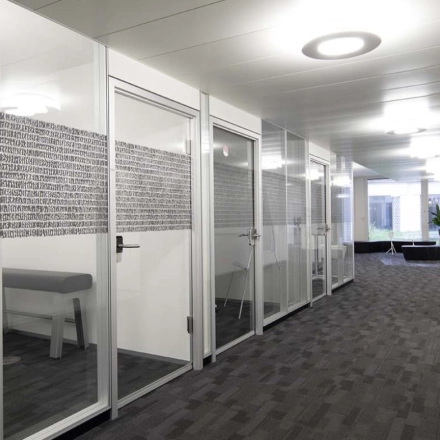 Modern office space for rent at Europaallee 41 in Zürich Mitte, featuring glass-walled meeting rooms and a well-lit hallway.