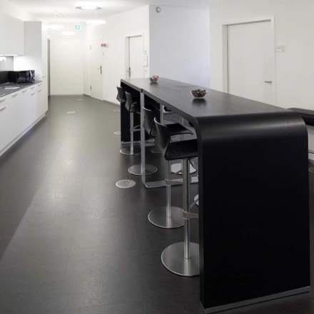 Modern office space with sleek kitchen facilities and high-top seating at Europaallee 41, perfect for office space rental in Zürich Mitte.