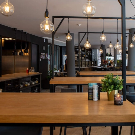 Modern office space rental in Zwolle with wooden tables and stylish lighting, offering a practical environment for business activities at Assendorperdijk 1.