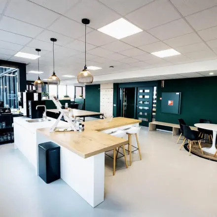 Furnished office space for rent at Hanzeplein 11-27, Zwolle, featuring modern design with a central countertop, seating area, and large windows.
