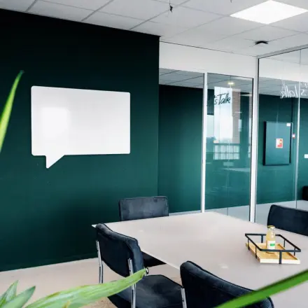 Modern office interior at Hanzeplein 11-27, Zwolle, featuring a sleek meeting table and chairs, ideal for office space rental. The dark green walls add a professional touch.
