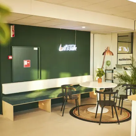 Cozy office space rental at Hanzeplein 11-27 in Zwolle, featuring seating and a neon sign saying 'Let’s Talk'. Ideal for businesses seeking a friendly office to rent.
