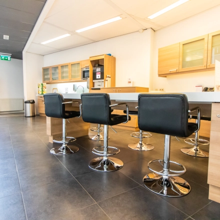 Espacio de oficina moderno en Madrid Arganzuela, Calle de Méndez Álvaro 20, ideal para alquilar una oficina, equipado con mesas, sillas y un área de cocina contemporánea.