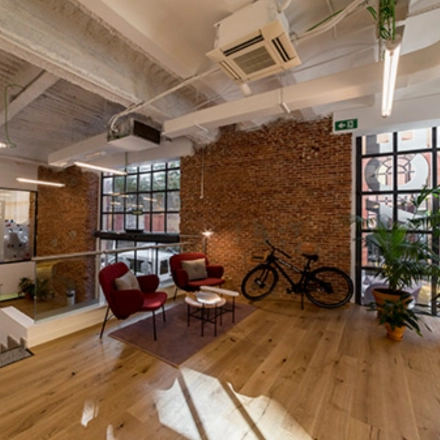 Espaciosa oficina en Manzanares 4, Madrid Centro, ideal para alquilar una oficina. Con diseño moderno, pisos de madera, y plantas decorativas, ofrece un ambiente acogedor.