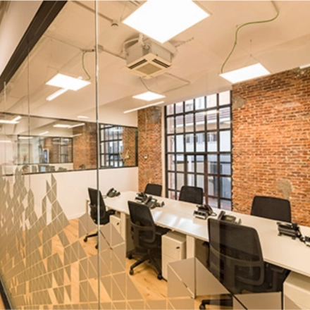 Espacio de alquiler de oficinas en Manzanares 4, Madrid Centro, con mesas y sillas modernas en un entorno luminoso con paredes de ladrillo visto.