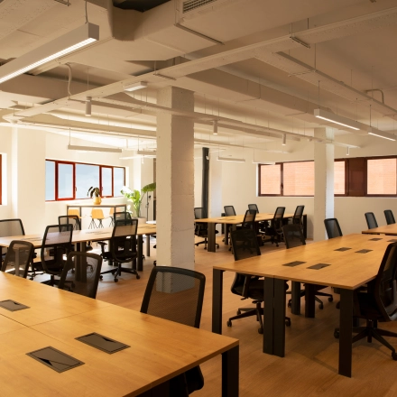 Vista de un espacio de alquiler de oficinas luminoso y espacioso en Paseo Imperial 14, Madrid Centro, con mesas de trabajo y sillas ergonómicas.