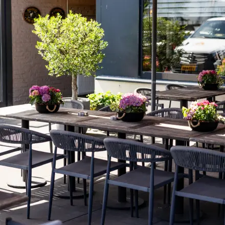 Terras aan Bedrijvenpark Twente 305 in Almelo met houten tafels, stoelen en planten, geschikt voor ontspannen vergaderingen of pauzes.