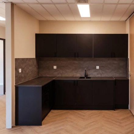Moderne kantoorruimte te huur op Jool Hulstraat 2-14 in Almere Stad met minimalistisch keukenblok en neutrale kleuren.