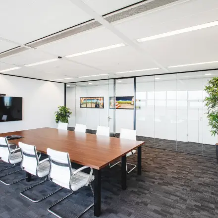 Moderne kantoorruimte in Almere Stad met ruime vergadertafel, witte stoelen en glazen wanden. Ideaal voor zakelijke bijeenkomsten. Geschikt voor kantoorruimte huren in een professioneel kantoorpand.