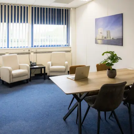 Kantoorruimte te huur op Markerkant 1310 in Almere Stad met een vergadertafel, stoelen, zithoek en een bloempot. Perfect voor een efficiënte werkdag.