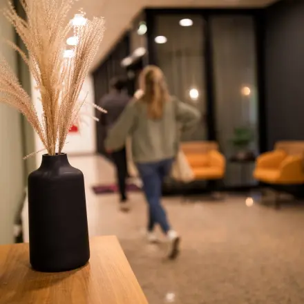 Moderne kantoorruimte huren in Almere Stad aan Markerkant 1310, met stijlvolle inrichting. Twee personen lopen door een gang langs comfortabele stoelen en decoratieve elementen.