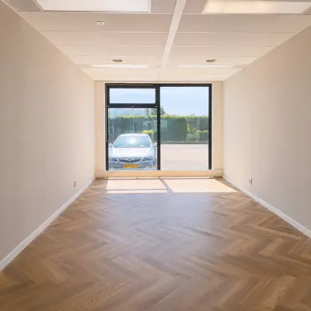 Kantoorruimte te huur op Veluwezoom 15 in Almere Stad met zicht op de parkeerplaats, voorzien van visgraat vloer en grote ramen voor natuurlijk licht.