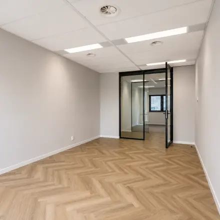Ongemeubileerde kantoorruimte te huur aan Veluwezoom 15 in Almere Stad met houten vloer en glazen deur, ideaal voor een persoonlijke touch in je nieuwe kantoor.