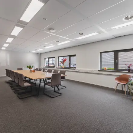 Ruime kantoorruimte te huur op Veluwezoom 15 in Almere Stad, met een lange vergadertafel en moderne stoelen, geschikt voor vergaderingen of coworking.