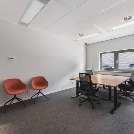 Kantoorruimte huren aan Veluwezoom 15 in Almere Stad met strak bureau en moderne stoelen, gelegen in een lichte ruimte met groot raam.