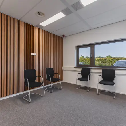Almere Stad biedt een gemeubileerde kantoorruimte met comfortabele stoelen en een houten accentwand. Ideaal voor bedrijven die op zoek zijn naar een kantoorruimte om te huren.