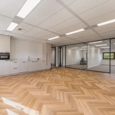 Kantoorruimte op Veluwezoom 15 in Almere Stad met een houten vloer, glazen wanden en een ingebouwde pantry. Ideaal voor wie een lichte werkplek wil huren.