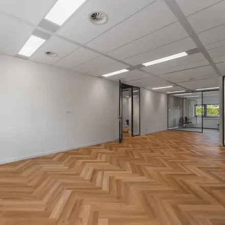 Moderne kantoorruimte op Veluwezoom 15 in Almere Stad met houten vloer en glazen tussenwanden. Ideaal om te huren voor een professionele werkomgeving.