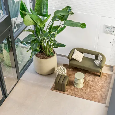 Entree van een kantoorpand op Maanlander 43 in Amersfoort Calveen met een stijlvolle loungehoek en grote groene planten.