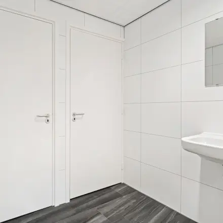 Wit betegelde toiletruimte in kantoorpand met wastafel en spiegel op Maanlander 43, Amersfoort Calveen. Kantoorruimte huren in een nette omgeving.