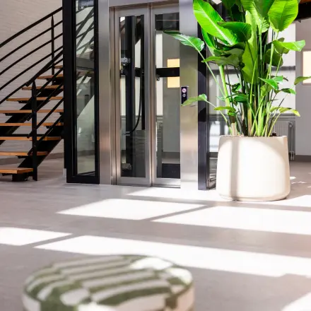 Moderne kantoorruimte in Amersfoort Calveen met een trap en lift bij de ingang, inclusief grote plant voor een natuurlijke uitstraling.