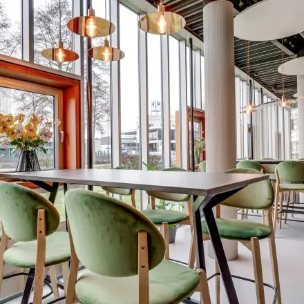 Moderne kantoorruimte met grote ramen en groene stoelen, ideaal voor wie kantoorruimte wil huren in Amersfoort Calveen.