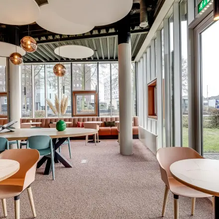 Moderne kantoorruimte in Amersfoort Calveen met grote ramen, stijlvolle meubilering en veel natuurlijk licht; ideaal om te huren voor creatieve werksessies.