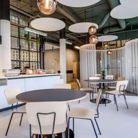 Moderne, goed verlichte kantine in een kantoorpand op Maanlander 47, Amersfoort Calveen. Stijlvolle tafels en stoelen, met een uitnodigende sfeer voor een ontspannen lunch of informele bijeenkomst. Ideaal voor kantoorruimte huren.