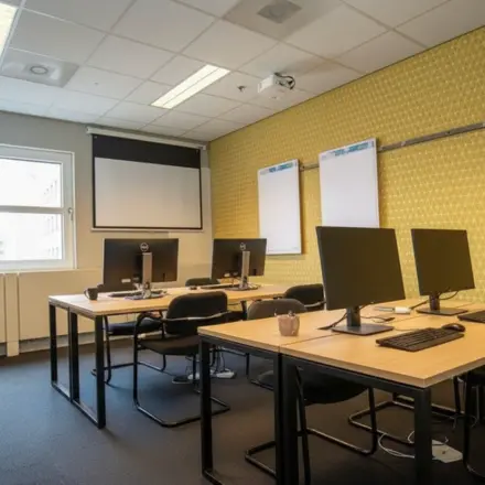 Moderne kantoorruimte in Amersfoort Centraal Station met drie bureaus, computers en een projector, ideaal voor werk of vergaderingen. Geschikt voor wie een kantoorpand wil huren op een centrale locatie.