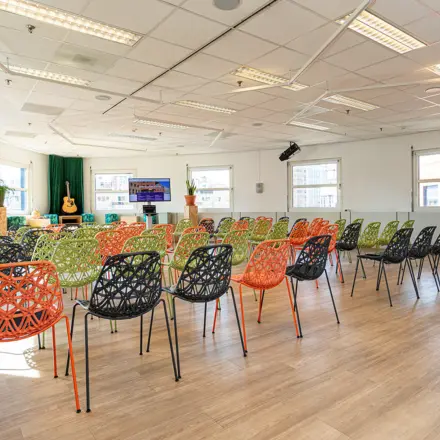 Ruime, lichte kantoorpand met kleurrijke stoelen en een podium voor presentaties, gelegen bij Amersfoort Centraal Station. Ideale plek om kantoorruimte te huren met flexibele indeling.