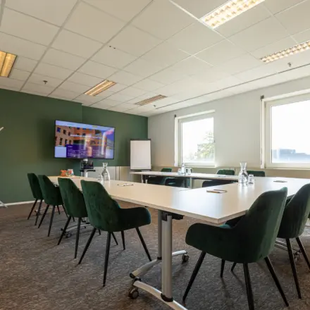 Vergaderzaal in kantoorpand op Stationsplein 49, Amersfoort Centraal Station met groene stoelen en conferentietafel. Ideaal voor kantoorruimte huren in een centraal gelegen kantoor.
