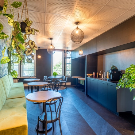 Stijlvolle kantoorruimte huren op Stadsring 115, Amersfoort Centrum, met groen aangeklede zithoek, ronde tafels en veel natuurlijk licht.