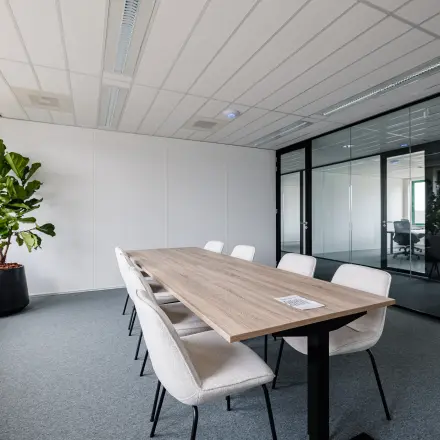 Lichte kantoorruimte met moderne vergadertafel en stoelen bij Stadsring 201 in Amersfoort Centrum. Glaswanden bieden uitzicht op andere kantoorruimten. Perfecte locatie om een kantoorpand te huren.