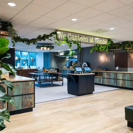 Kantoorruimte huren op De Gondel 1 in Amstelveen. Moderne kantine met veel groen, houten details en zitplaatsen. Geschikt voor informele bijeenkomsten en lunchpauzes.