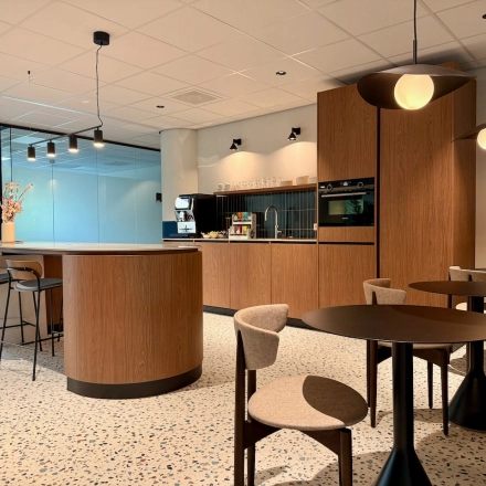 Moderne, lichte kantoorpand pantry op Professor E.M. Meijerslaan 1 in Amstelveen met ronde tafels, barkrukken en ingebouwde keukenapparatuur. Perfect om kantoorruimte te huren voor creatieve pauzemomenten en informele vergaderingen.