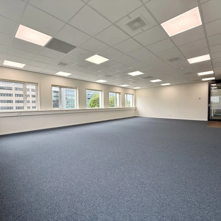 Lege kantoorruimte op Professor E.M. Meijerslaan 1, Amstelveen, met witte muren, een blauw tapijt en meerdere ramen die natuurlijk licht binnenlaten.