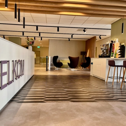Moderne entree van een kantoorpand op Professor E.M. Meijerslaan 1 in Amstelveen. Het interieur is strak met een welkom bord en stijlvolle meubels, ideaal om als kantoorruimte te huren.
