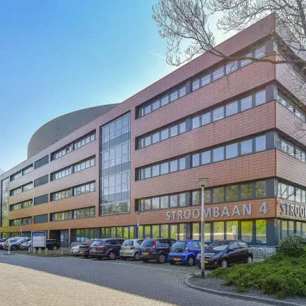 Buitenaanzicht van het kantoorpand Stroombaan 4 in Amstelveen, met zicht op parkeerplaatsen aan de voorkant van het gebouw.