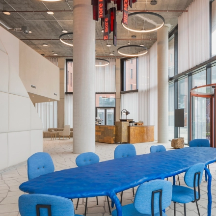 Moderne kantoorpand gelegen op H.J.E. Wenckebachweg 230-258 in Amsterdam Amstel Business Park, met opvallende blauwe vergadertafel en design verlichting.