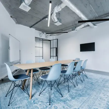 Moderne kantoorruimte met een lange tafel en blauwe stoelen op H.J.E. Wenckebachweg 90-108, geschikt voor vergaderingen of teamwork in Amsterdam Amstel Business Park.