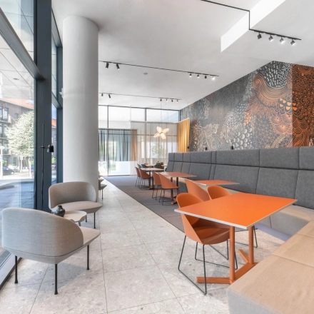 Gezellig ingerichte lounge in het kantoorpand op Trompenburgstraat 2c, Amsterdam Amstel Business Park. Moderne zitruimte met kleurrijke stoelen en veel natuurlijk licht, ideaal voor informeel overleg of pauzes tijdens het werken.