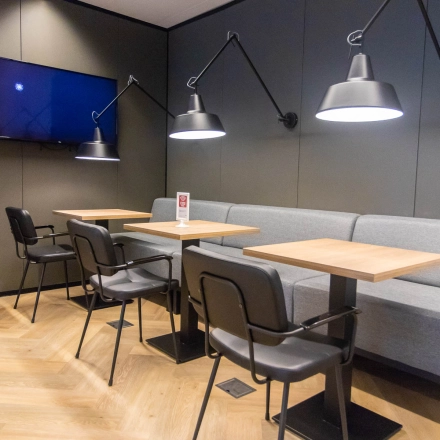 Moderne kantoorruimte met houten vloer en stijlvolle verlichting op Amstelplein 8, Amsterdam Amstel. De ruimte beschikt over tafels en stoelen, perfect voor huur als werkplek of vergaderruimte.