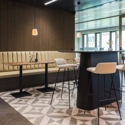 Moderne kantoorruimte huren in Amsterdam Buitenveldert op Walborg 2A met stijlvolle zithoek en hoge stoelen, ideaal voor informele vergaderingen.