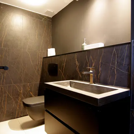 Moderne, stijlvolle toiletruimte in het kantoorpand op Kleine Gartmanplantsoen 21, Amsterdam Centrum, met donkere wandtegels en strakke wastafel. Ideaal voor wie kantoorruimte wil huren.