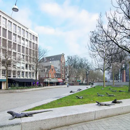 Buitenzijde van kantoorpand op Kleine Gartmanplantsoen 21 in Amsterdam Centrum, omringd door bomen en straatkunst. Mogelijkheid voor kantoorruimte huren in de drukke binnenstad.