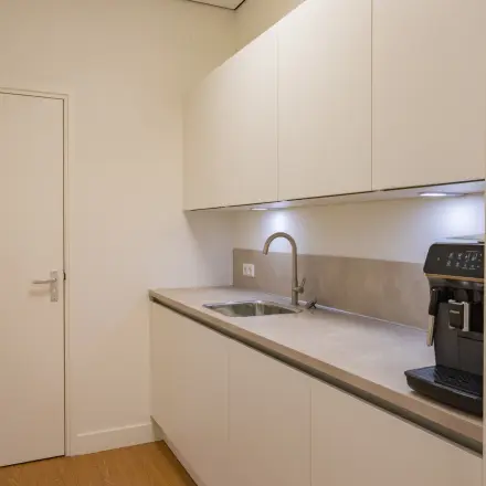 Moderne pantry in kantoorpand op Korte Leidsedwarsstraat 133A, Amsterdam Centrum, met witte kasten en espressomachine, ideaal voor huur in deze kantoorruimte.