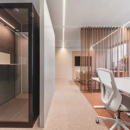 Moderne kantoorruimte huren met strakke inrichting, inclusief glazen scheidingswand en comfortabele witleren stoelen aan een vergadertafel op de Piet Heinkade in Amsterdam Centrum.