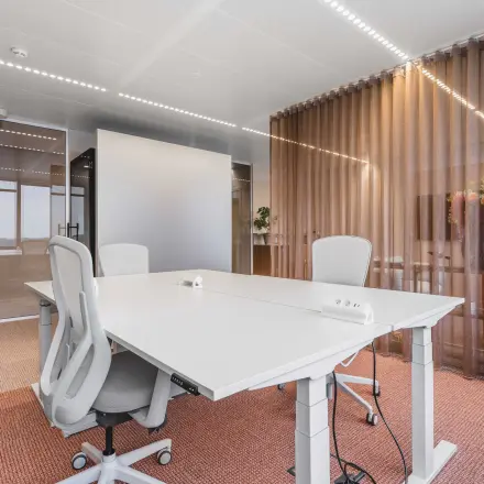 Moderne kantoorruimte voor verhuur in Amsterdam Centrum aan Piet Heinkade 55, met witte bureaus, ergonomische stoelen en glazen wanden, ideaal voor zakelijke ontmoetingen.