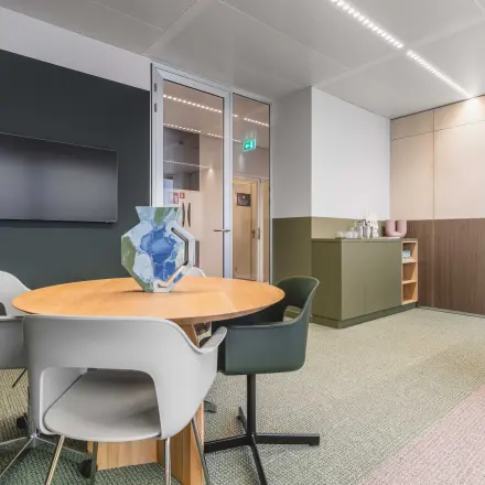 Kantoorruimte huren in modern kantoorpand aan de Piet Heinkade 55, Amsterdam Centrum. Stijlvolle vergadertafel met stoelen, geschikt voor zakelijke bijeenkomsten. Neutrale kleuren en glazen deuren creëren een lichte en open sfeer.