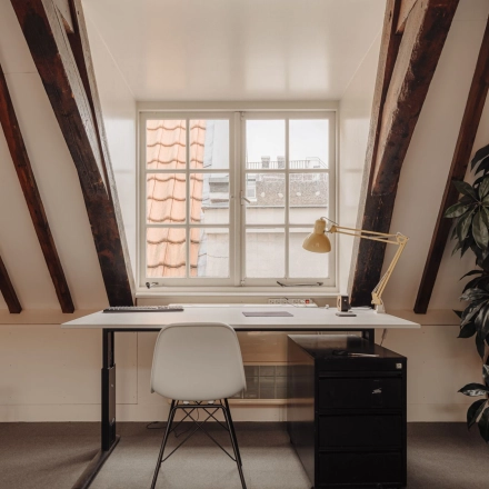 Lichte en knusse kantoorruimte huren op zolderverdieping bij Prins Hendrikkade 14, Amsterdam Centrum, met houten balken en een bureau voor stijlvol werken.